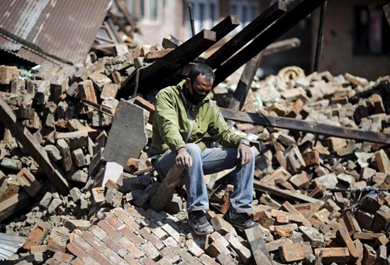 A man sits on the rubble of his damaged house in Bhaktapur, April 27, 2015. REUTERS/Adnan Abidi